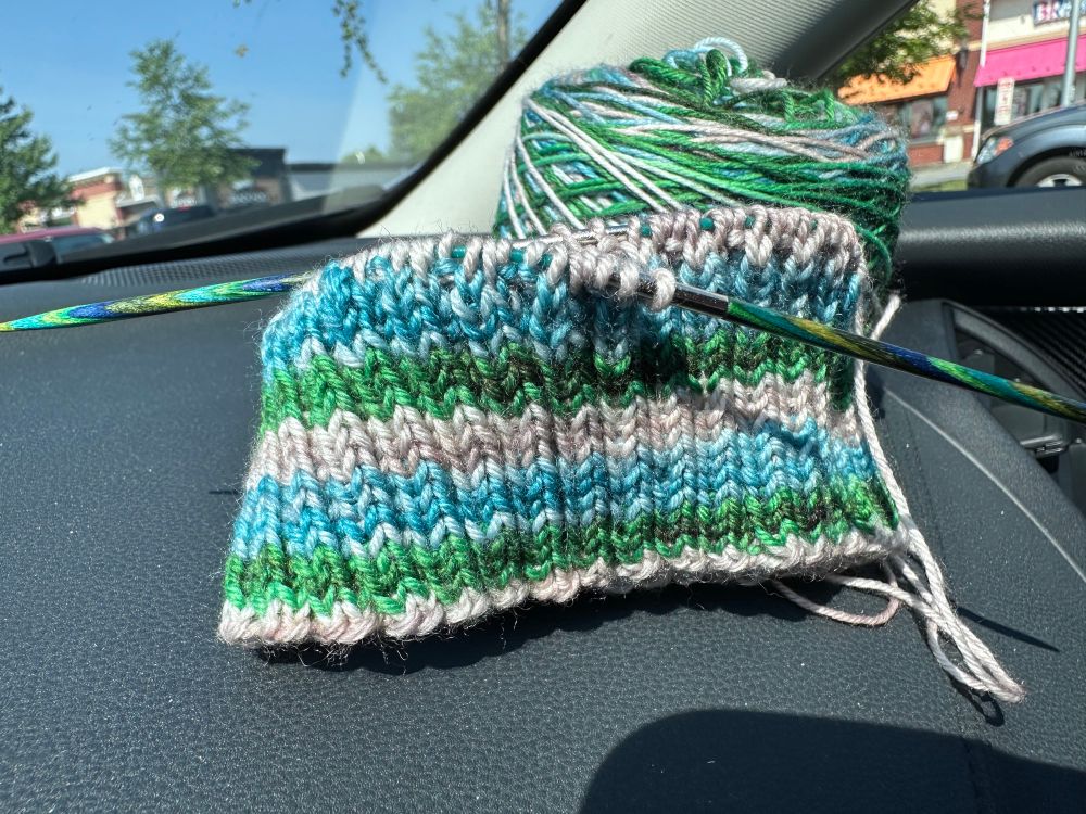 Green, gray, and blue striped knit hat ribbing on a black car dashboard