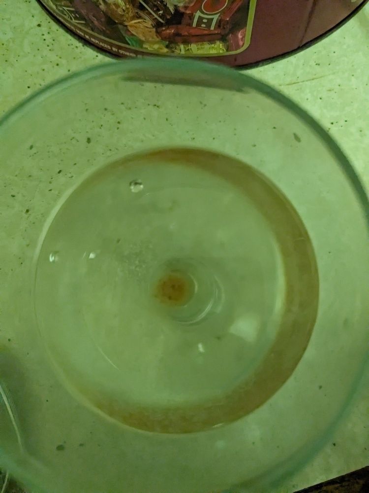 Glass of wine with grains of stock cube settled at the bottom.