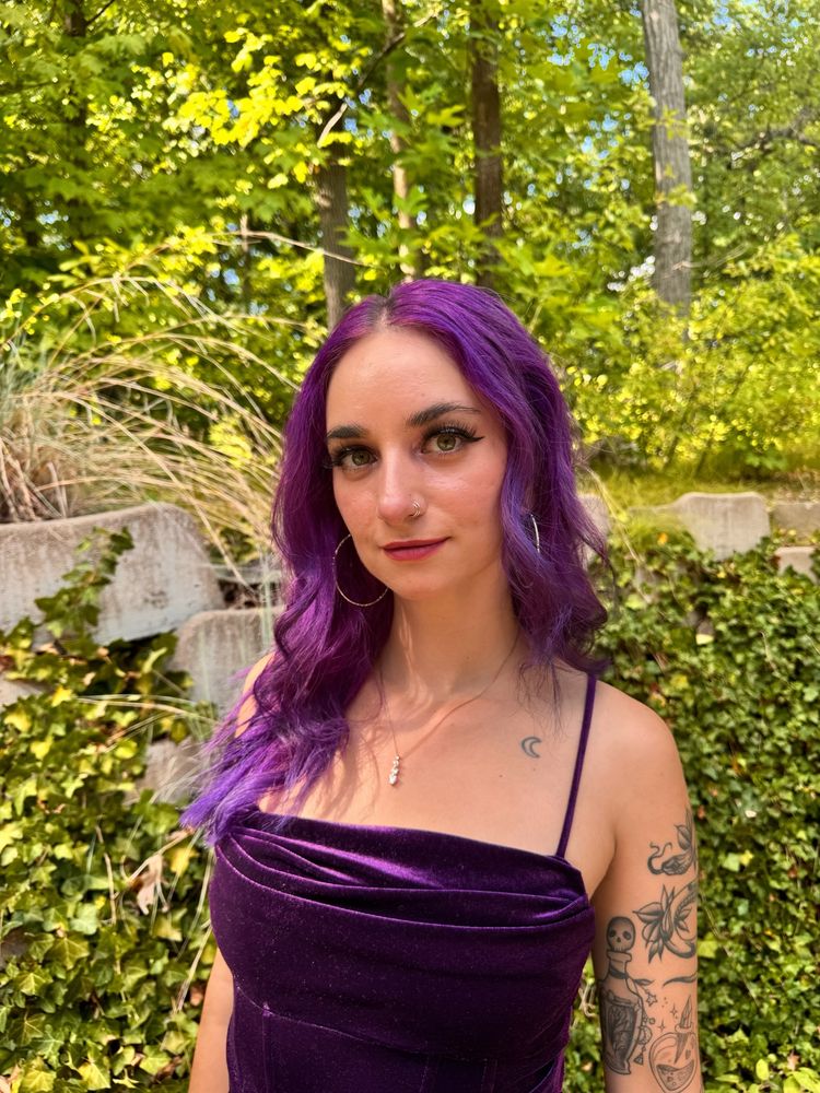 A photo of Jupie taken at an outdoor wedding with beautiful green foliage in the background 