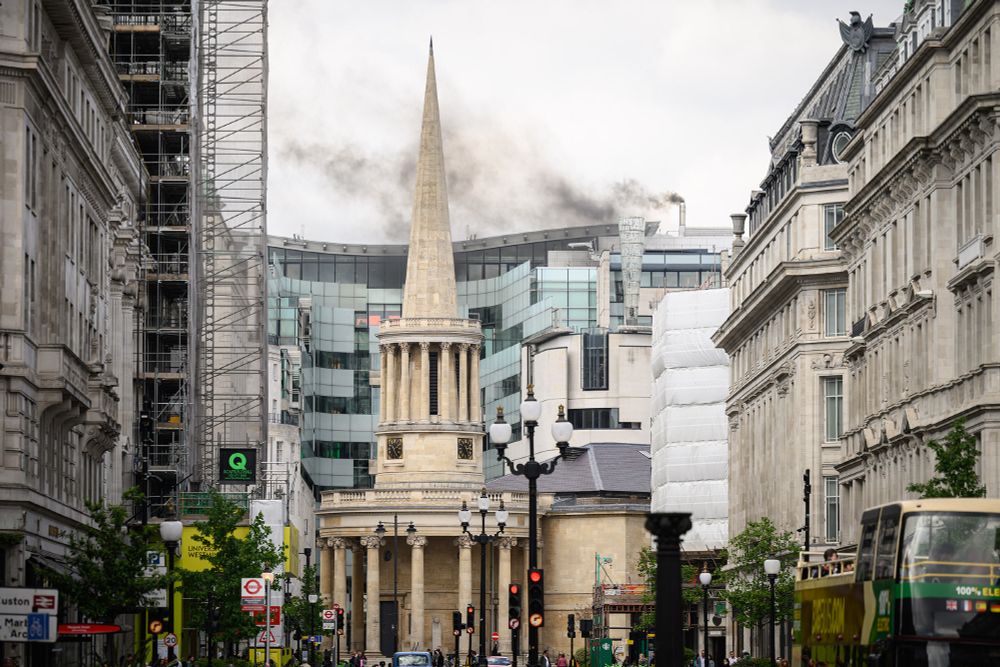 Black smoke rises from a chimney on a roof next to the BBC Broadcasting House,