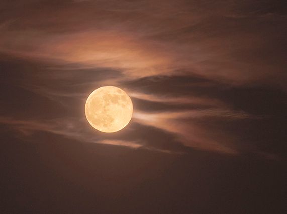 A full moon with clouds trailing like jets.