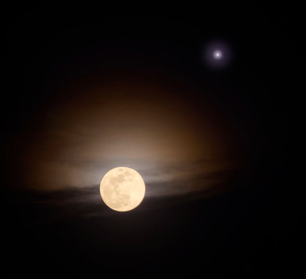 The full moon with a reddish aura and Venus shining on the upper right.