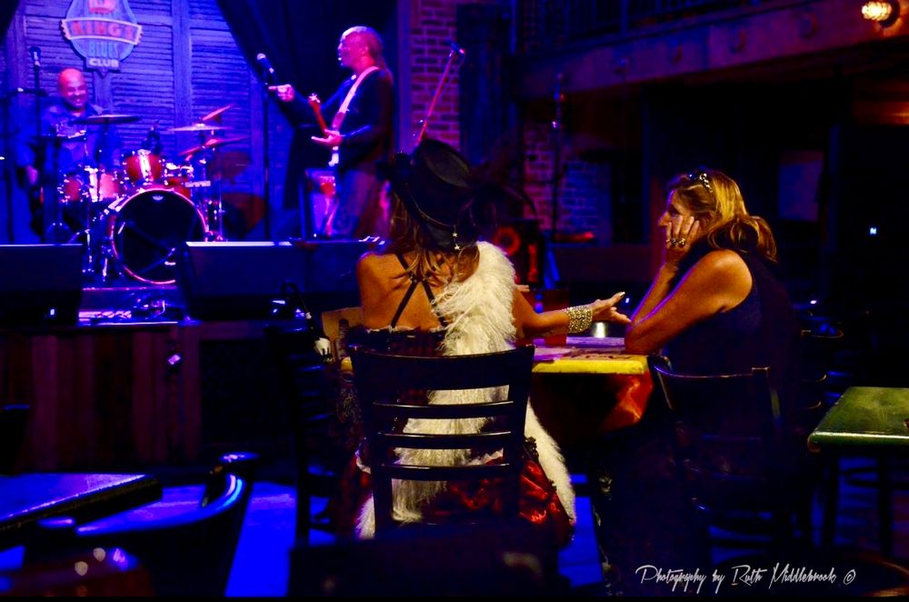 Women inside a bar, sitting at a table, listening to the band in New Orleans