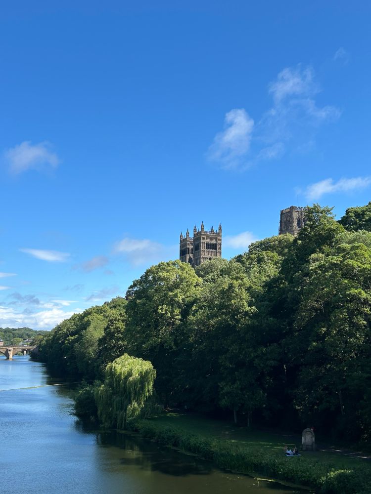 The towers of Durham cathedral visible over the trees with the river in the foreground