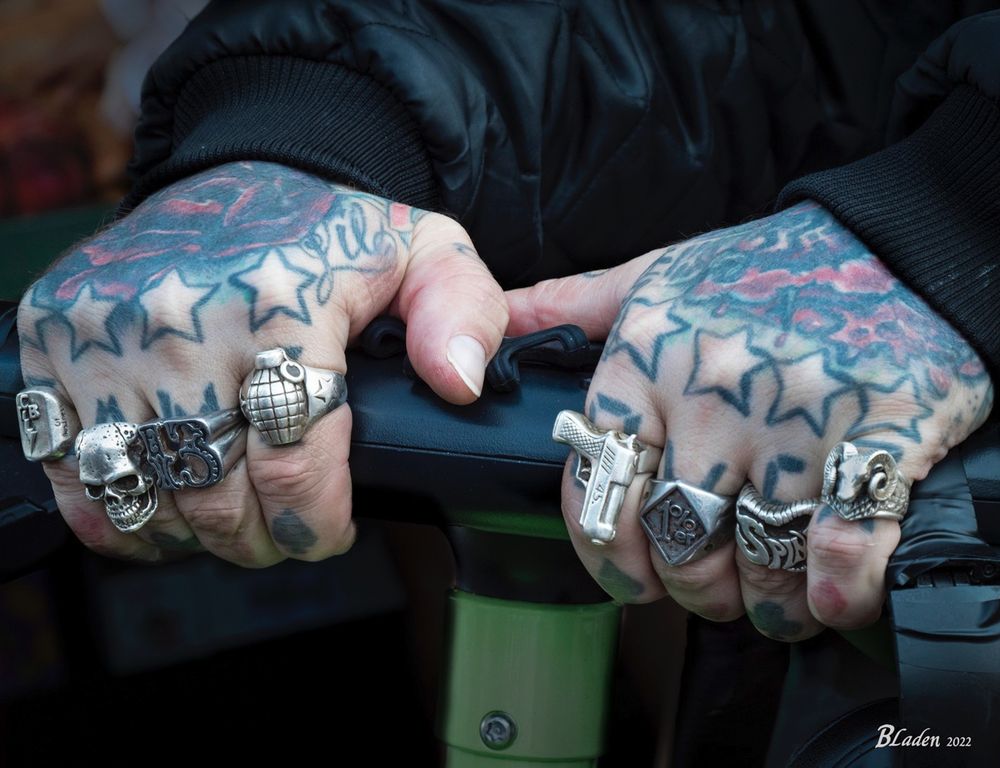 Hands with many tattoos and a ring on every finger.