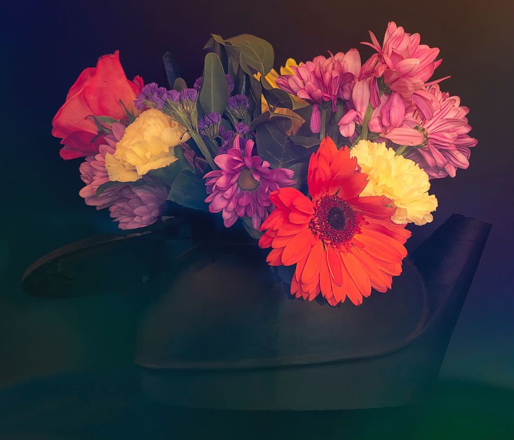A black cast iron kettle full of colorful flowers.