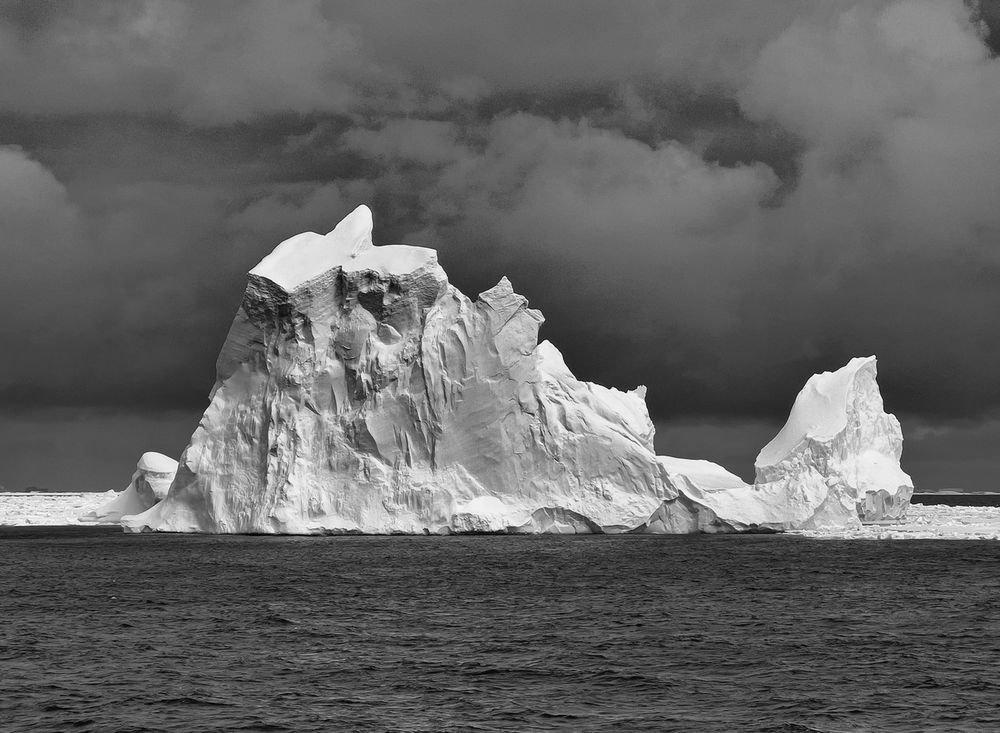 A black and white image of a very large ice berg floating in Antarctica.