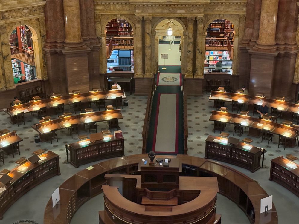 The congressional reading room, an elegant series of lit desks with shelves of books in the background, library of congress.