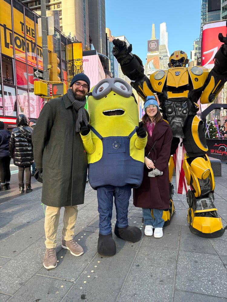 a picture of ZSeabeard and Erica with a minion at Times Square. photobombed by a transformer