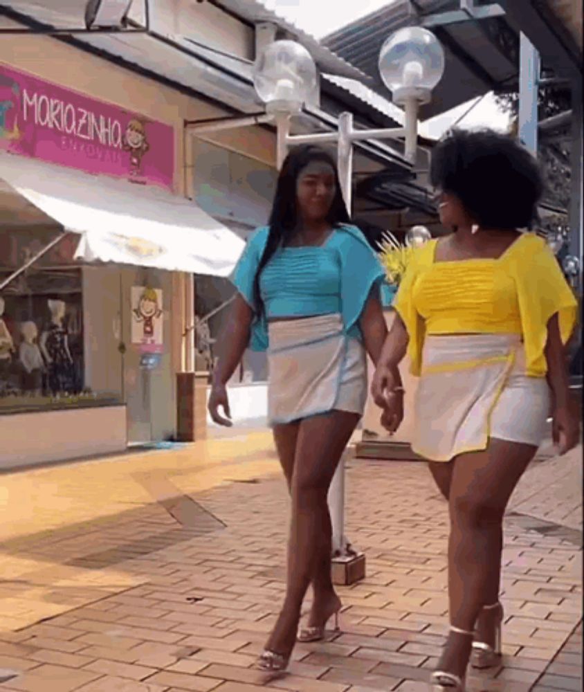 two women are walking down a sidewalk in front of a moriozinho store