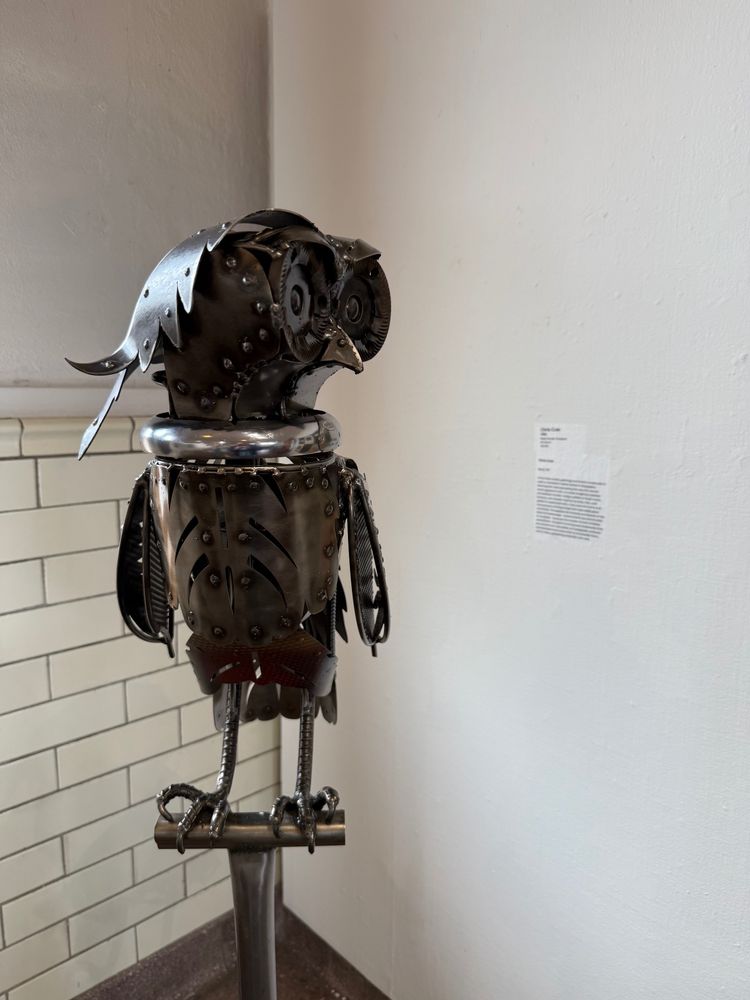 Kinetic sculpture of an owl made of rebar and sheet metal. The head is mounted on a bike wheel hub so spins freely.