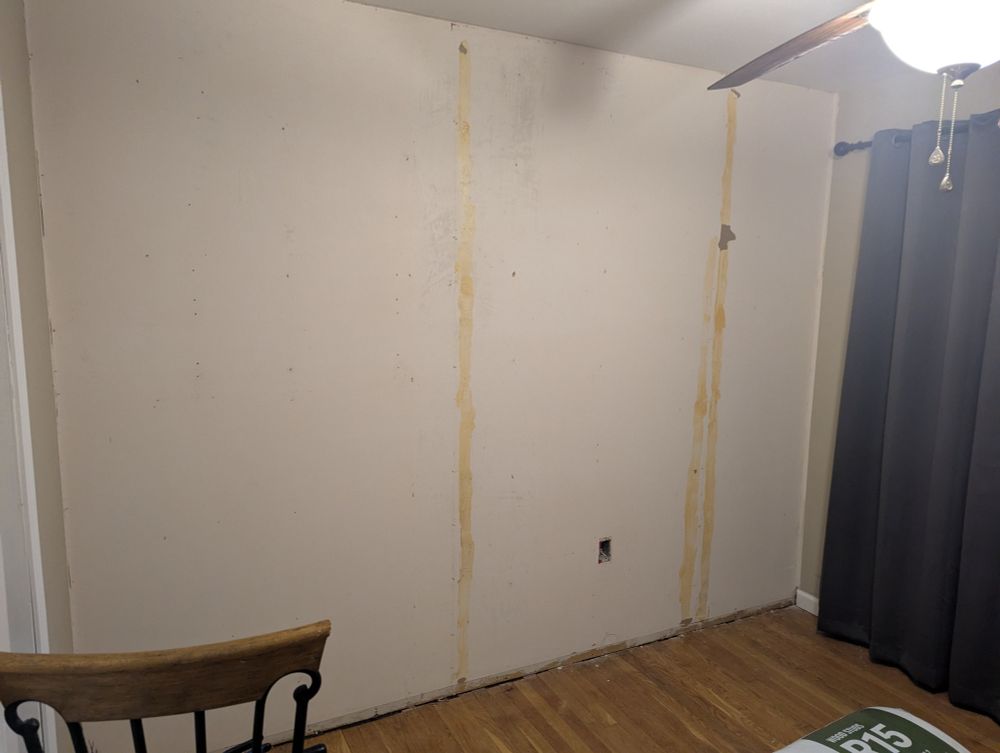 Drywall exposed after removing paneling that was installed over it with the face slightly torn in 2 places where it appears that an adhesive was applied