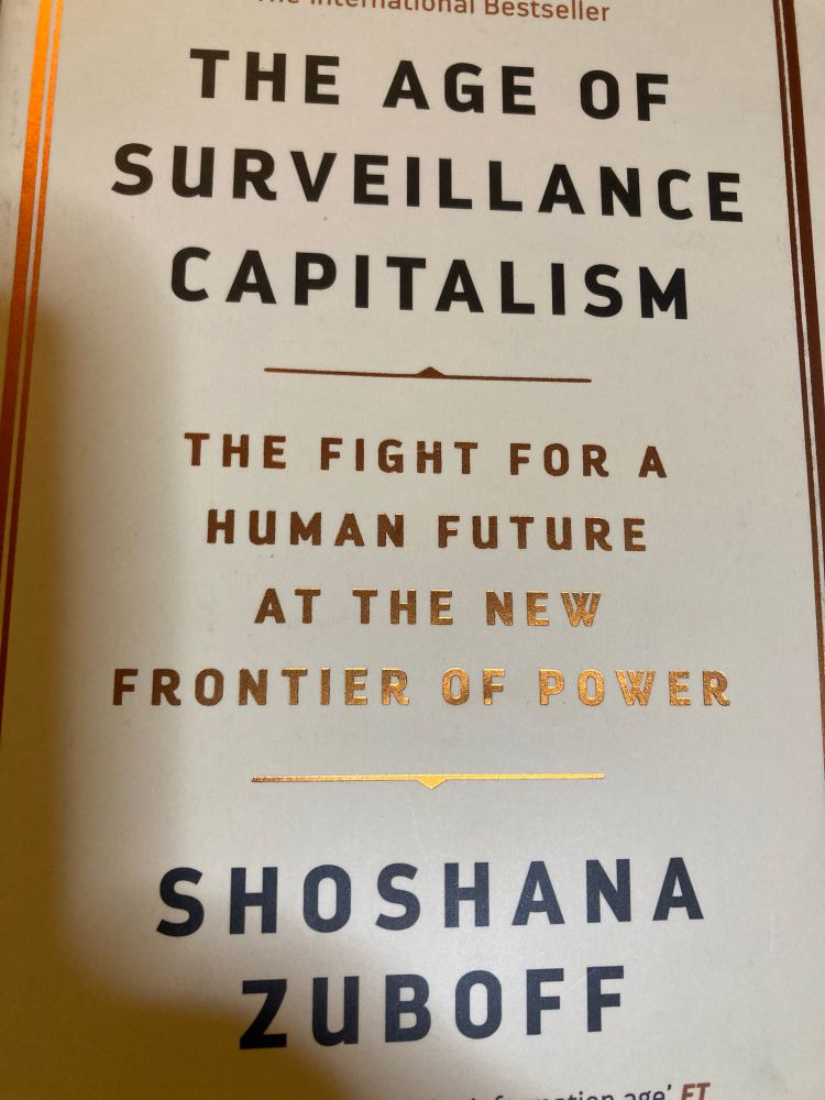 A close up of the cover of The Age of Surveillance Capitalism by Shoshana Zubhoff. The subtitle is The Fight for a Human Future at the New Frontier of Power. The book cover is white with black all caps text apart from the subtitle which is printed in gold, although that too is all caps. 