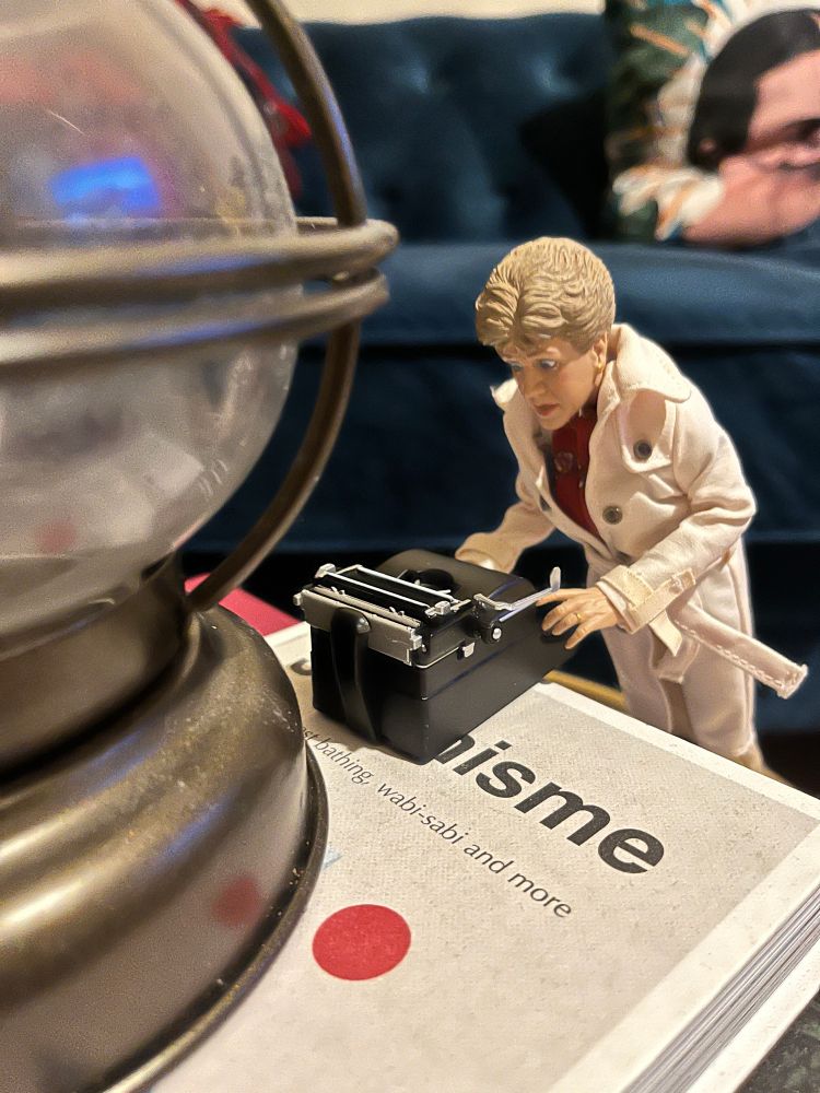 Jessica Fletcher figure leaning over a manual typewriter staring at it intently 