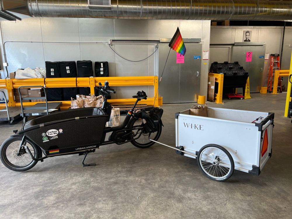 Bakfiets in a garage towing a trailer
Jeremy Cole with the food bank haul, volunteering

"Trailers are good. Cargo bikes are good. E-bikes are good. An e-cargo-bike towing a trailer is (at least) triple good.

Seen here loading grocery bags at the White Center Food Bank for my volunteer home delivery route"

America, US