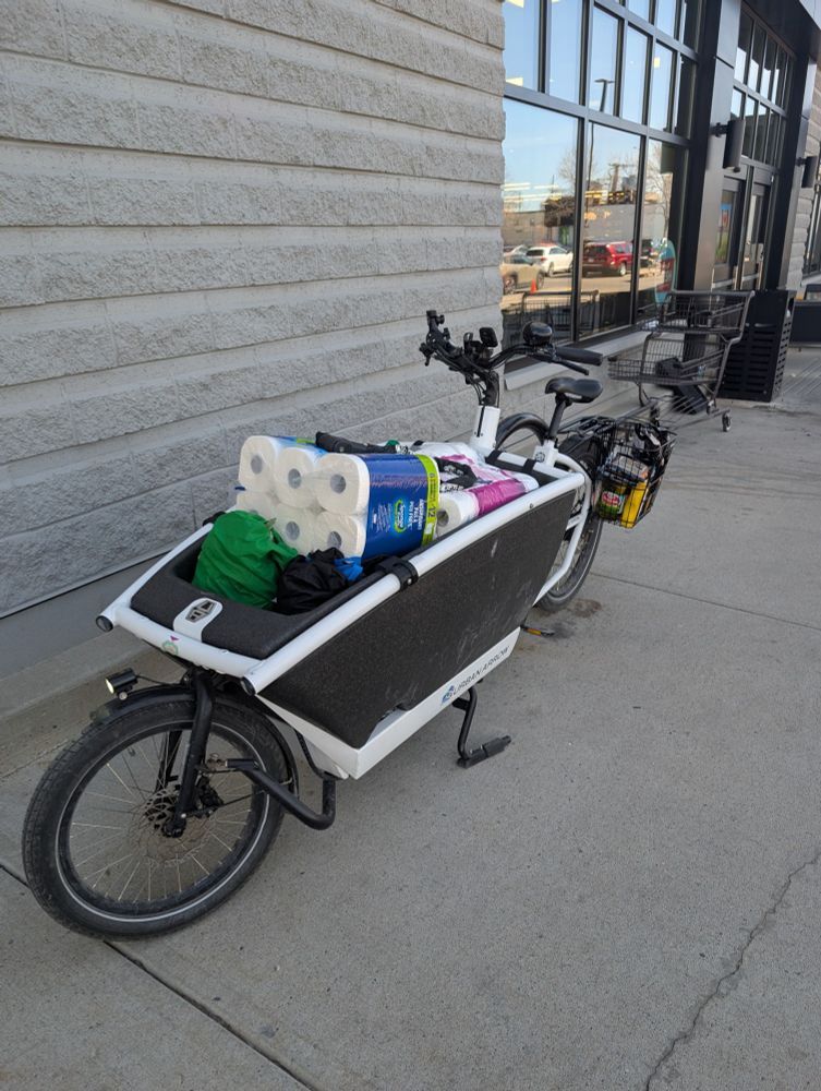 A bakfeits loaded to the gills with groceries, paper towels, parked outside a building