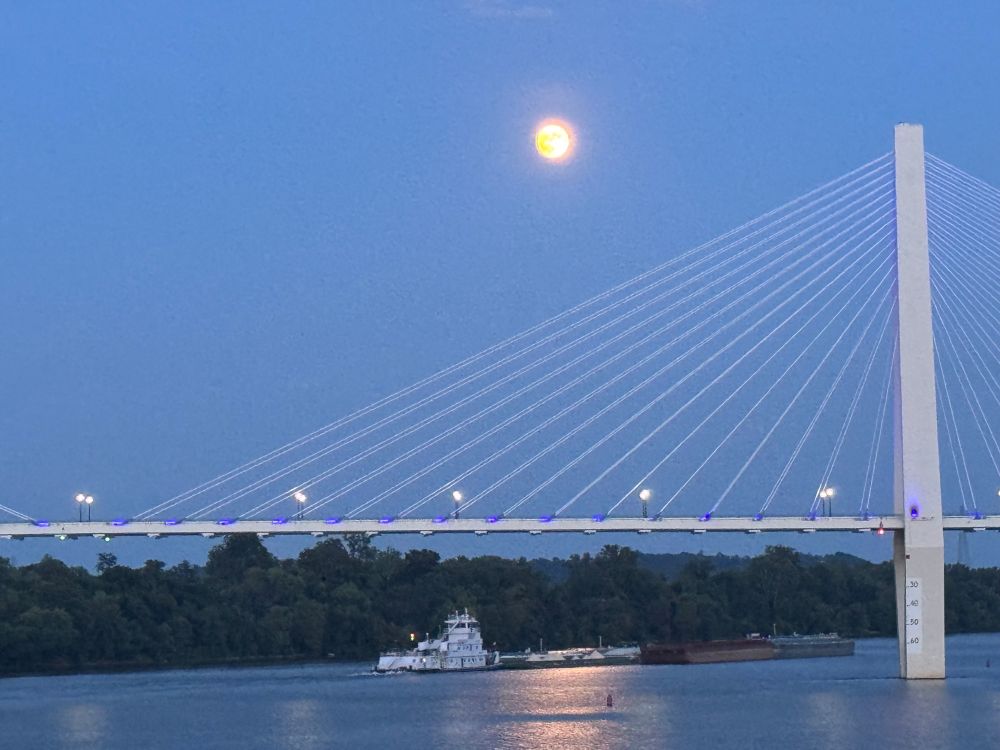 Barge on the river under a bridge, full moon above