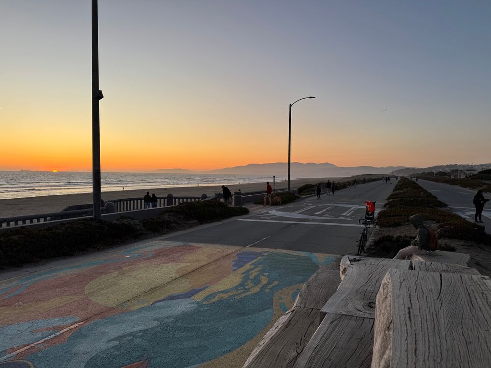 Picture of the sunset over ocean beach in SF with the sunset dunes park stretching in the distance on the right 