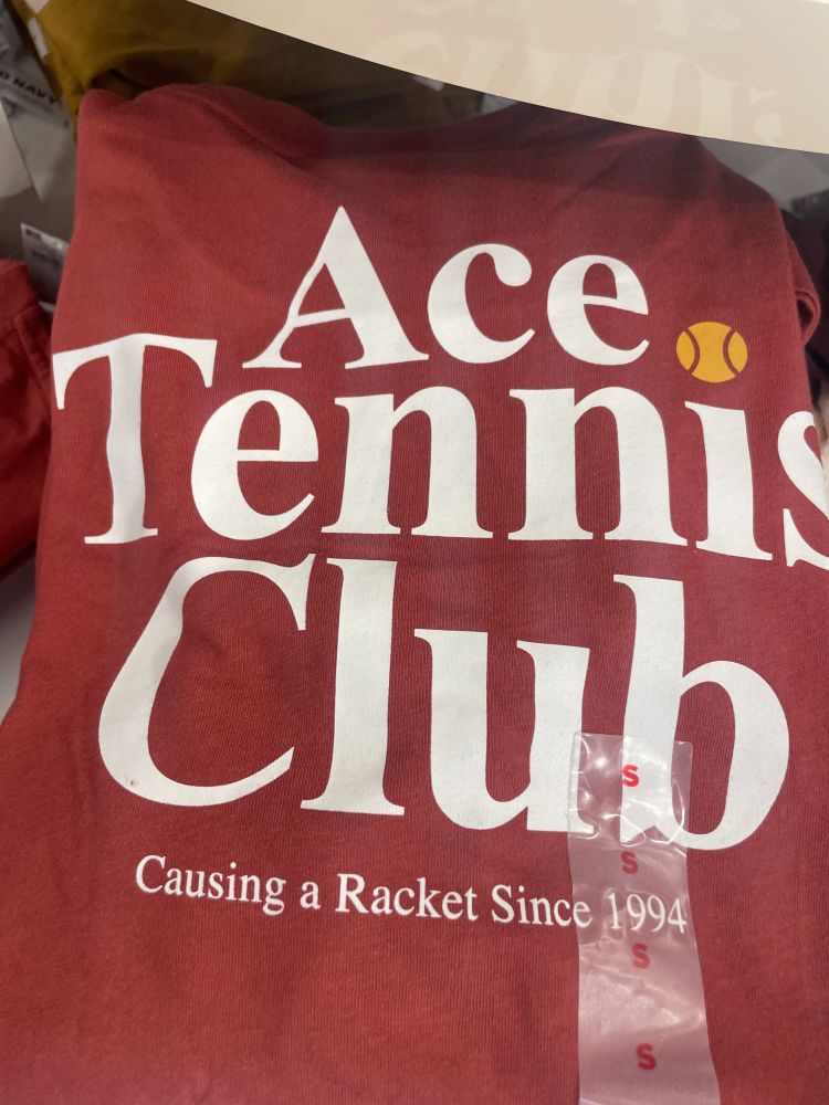 red tshirt Ace Tennis Clubs Causing a Racket since 1994. Tennis ball dotting the I