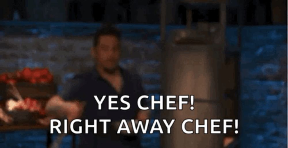 a man is standing in front of a brick wall with the words yes chef right away chef .