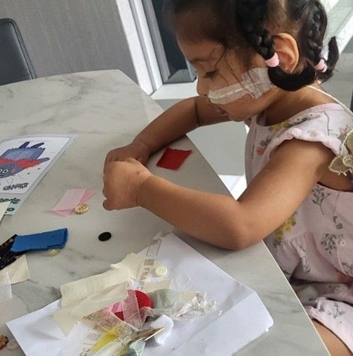 a small child making a collage with small bits of paper