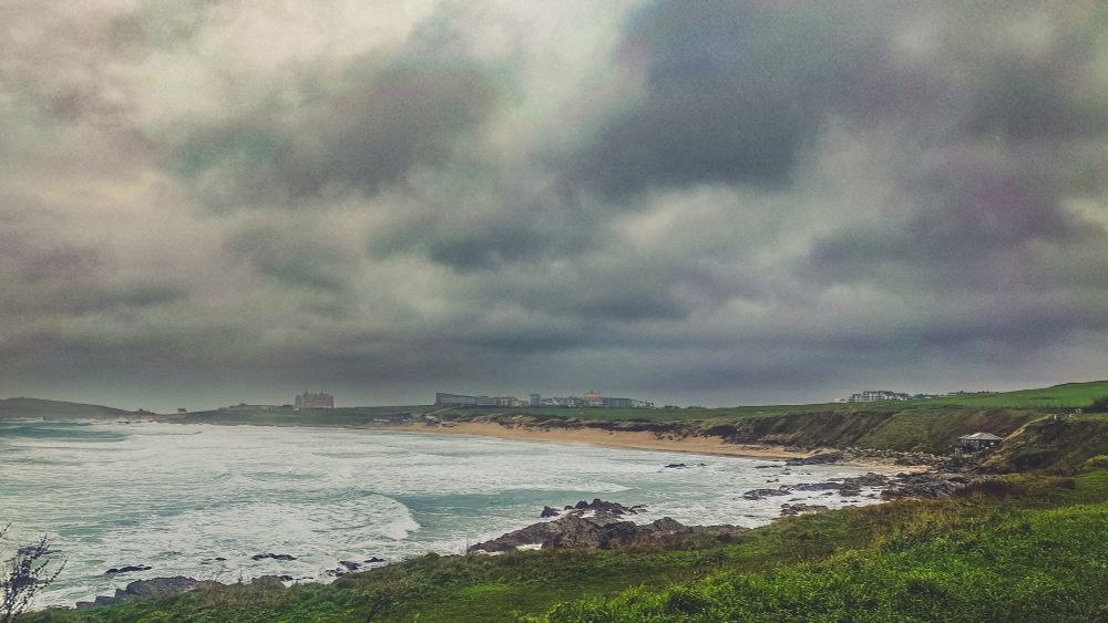 A scene across Fistral beach in Newquay, Cornwall. Dark clouds above and a choppy sea in the foreground 