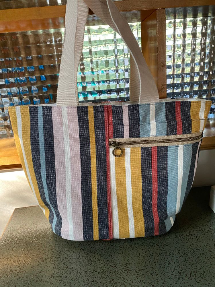 A tote bag made with multicolor striped canvas fabric. 
