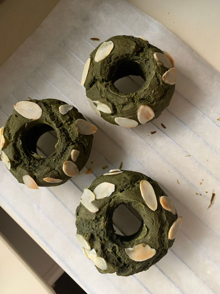 豆腐焼きドーナツの写真です。アーモンドスライスをトッピングした煎茶味のドーナツを、金網の上で冷ましているところです。