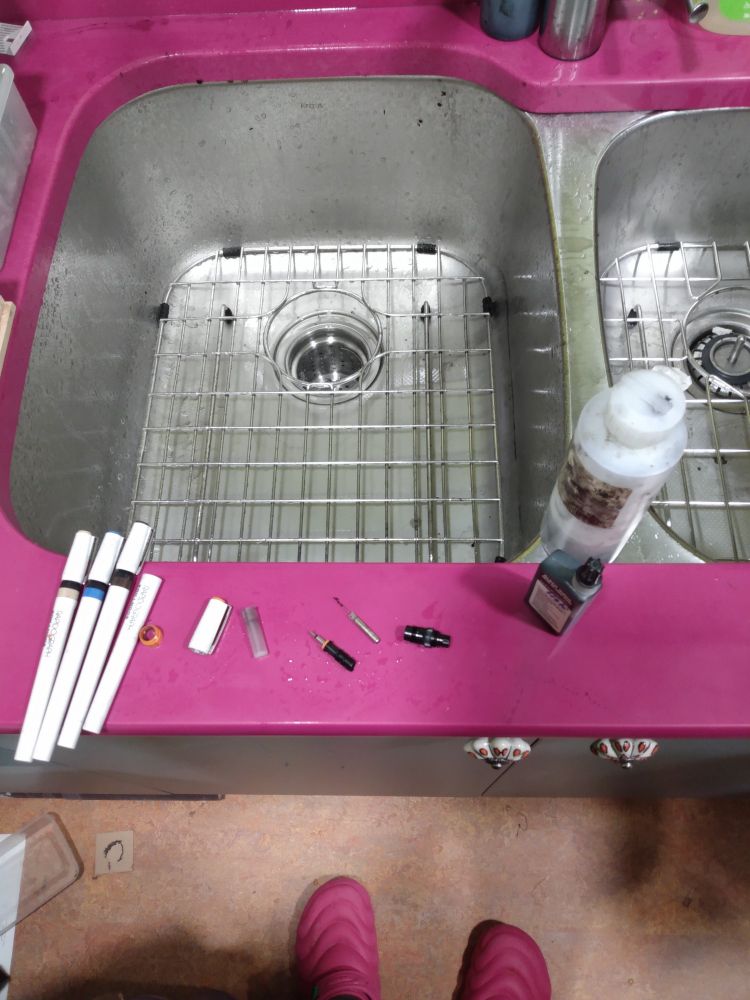 Rapidograph pens being cleaned at a sink set into a fabulous pink countertop but someone wearing fabulous pink shoes. 