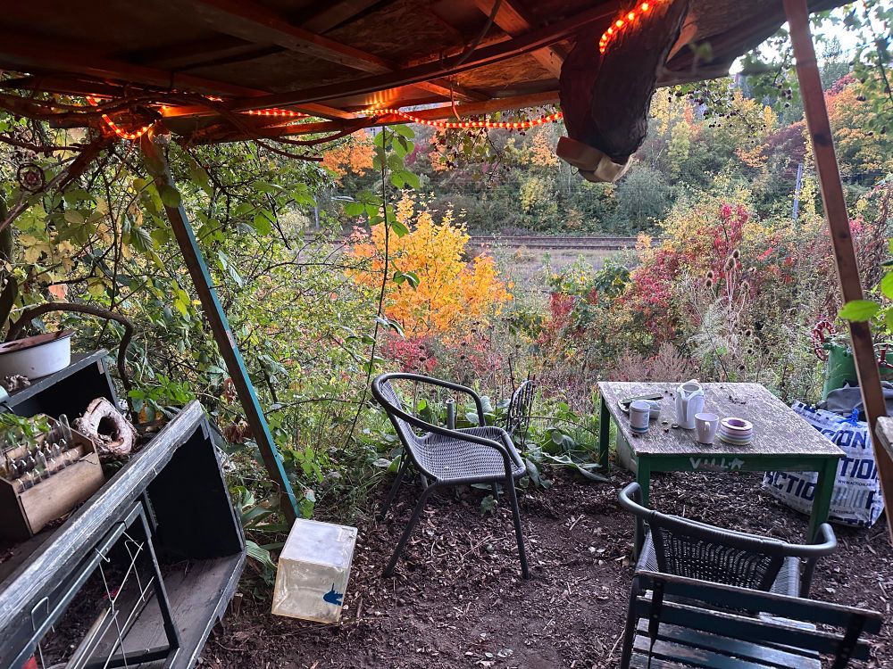 Flimsy chairs and a table looking out over train tracks 