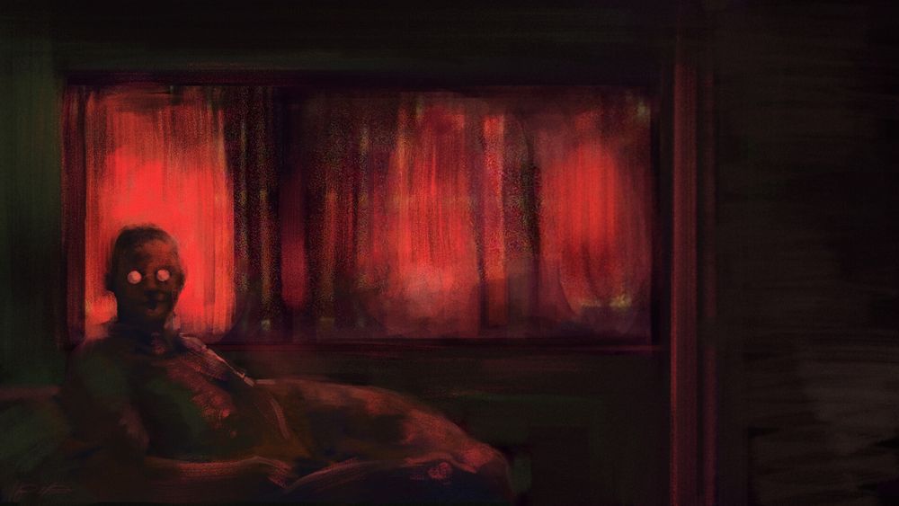 A dark room bathed in red light, a man with glasses stares expectantly at the viewer