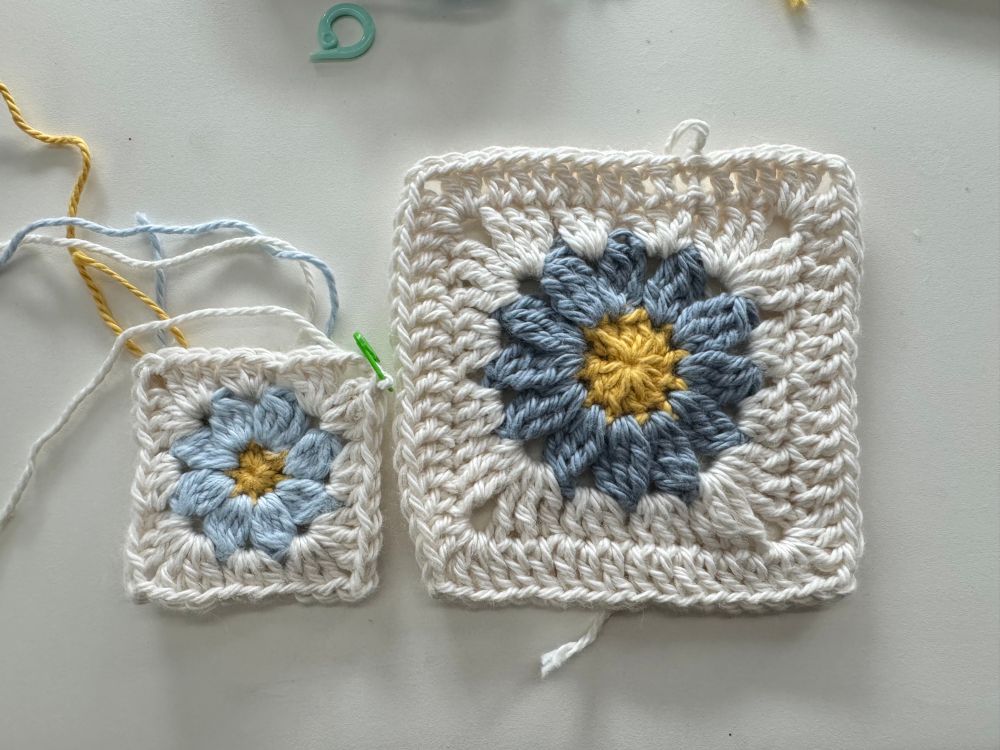 Two daisy granny squares in cream, blue, and yellow placed side by side, with one being half the height of the other.