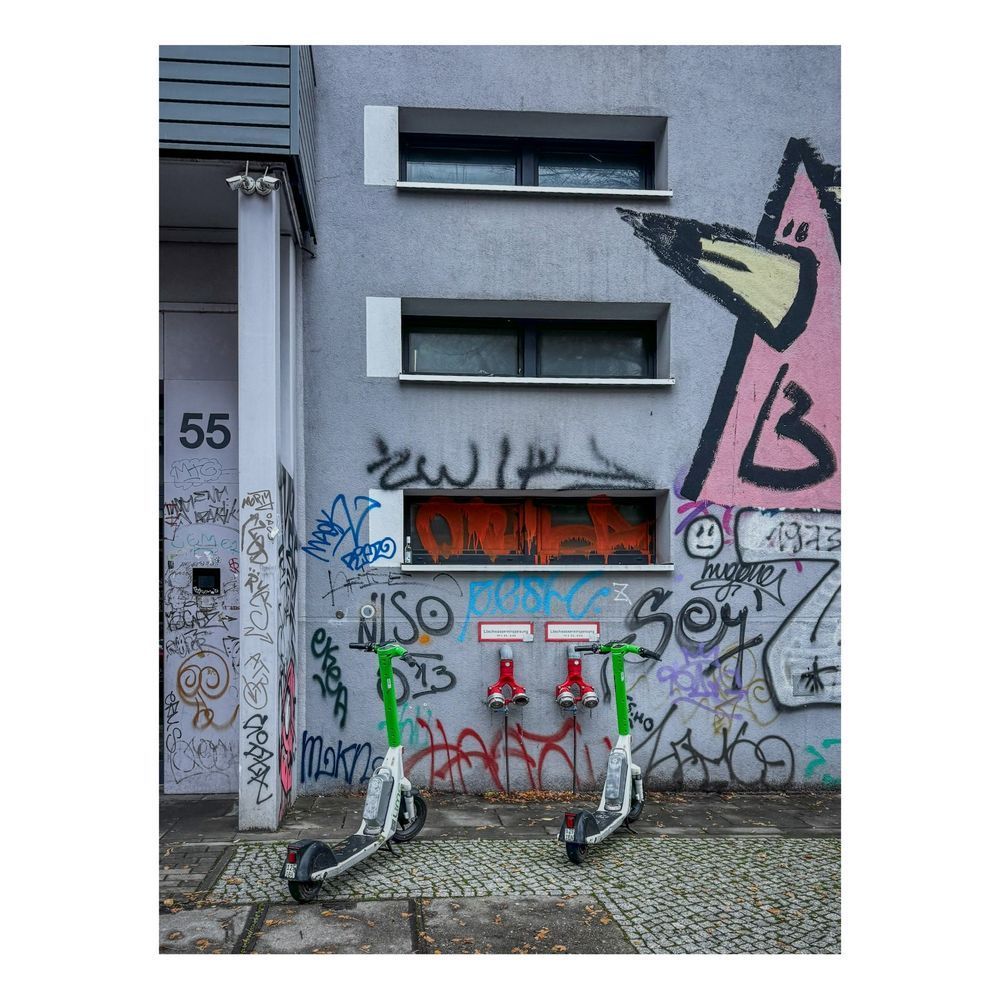 A pair of electric scooters and some serious graffiti can’t hide the beauty of two Siamese hydrants protruding from the wall. 