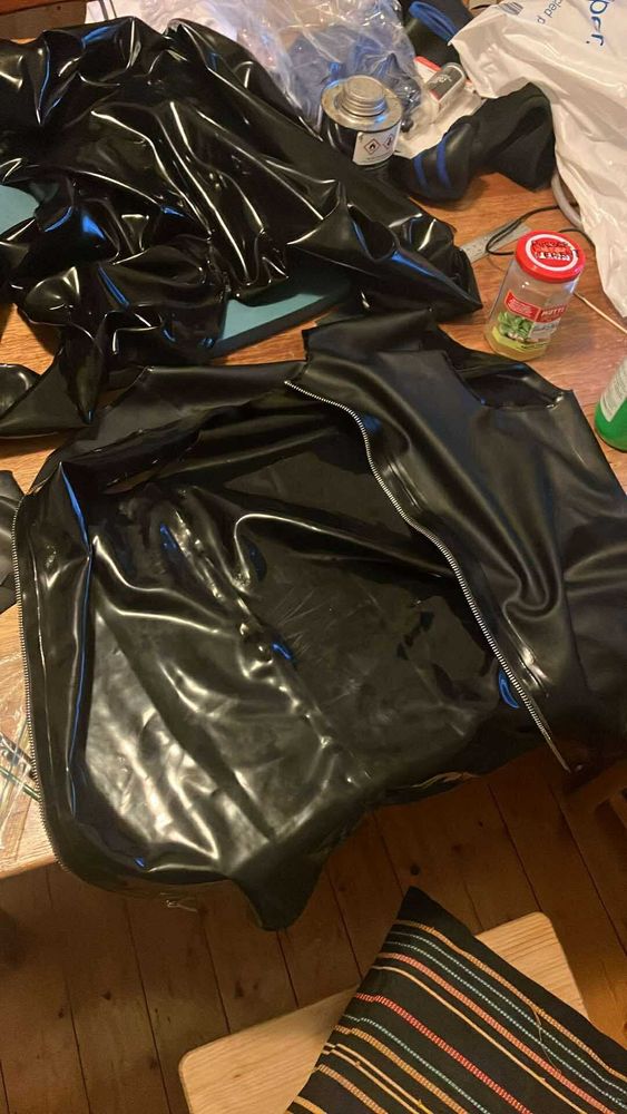 Various black latex items on a wooden table with cutting board, glue pot, brushes etc. 