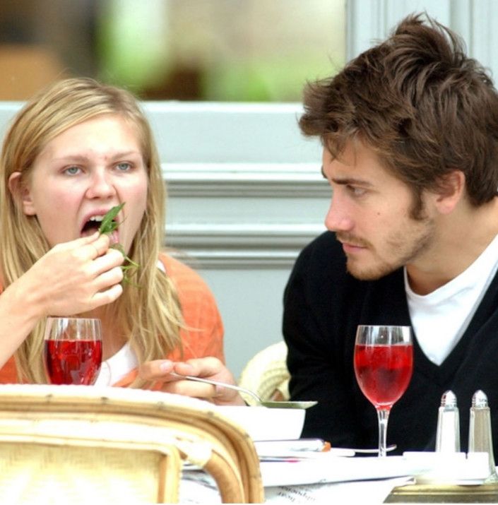 kirsten dunst putting salad in her mouth while jake gylenhall studies her