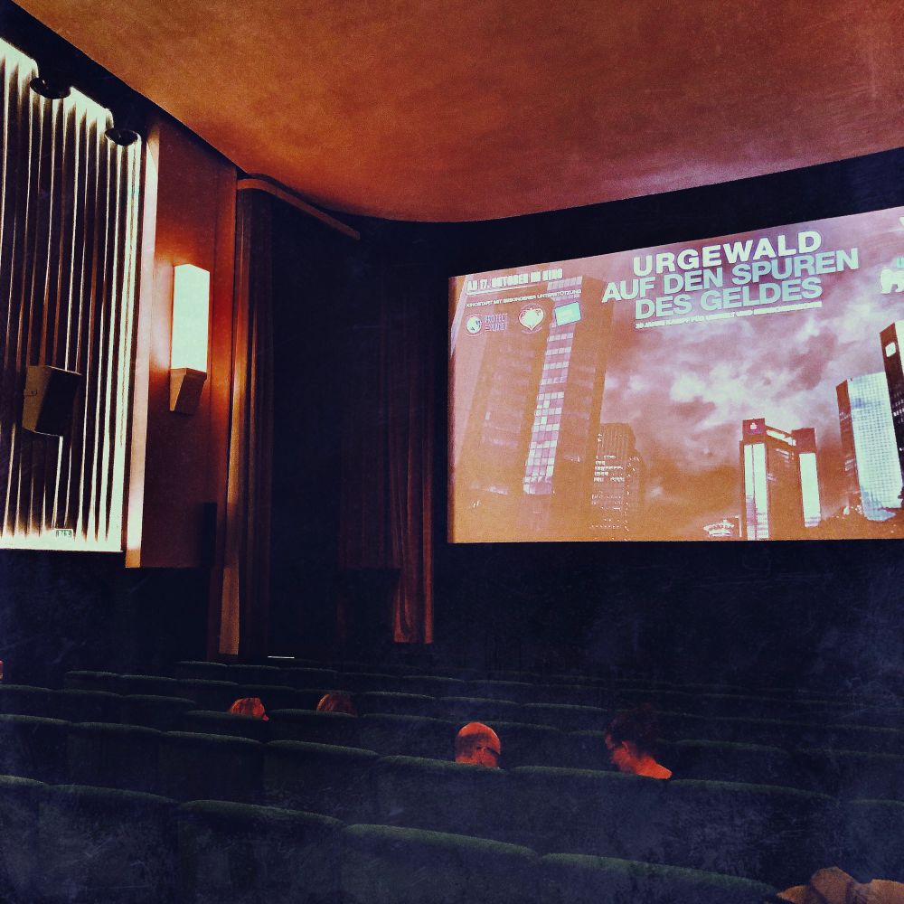 Saal 1 des Kant-Kinos Berlin. Auf der Leinwand das Standbild zum Film „Urgewald – Auf den Spuren des Geldes“.