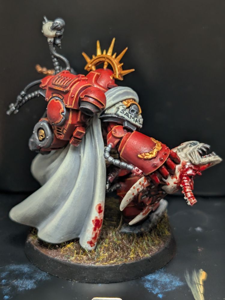 Captain in grav armor painted in Blood Ravens colors, holding a tyranid warrior head. Photo from the rear right.