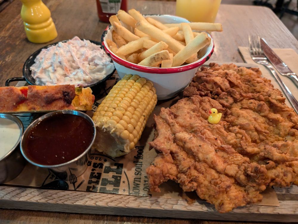A tiny plastic duck on top of a large fried chicken breast