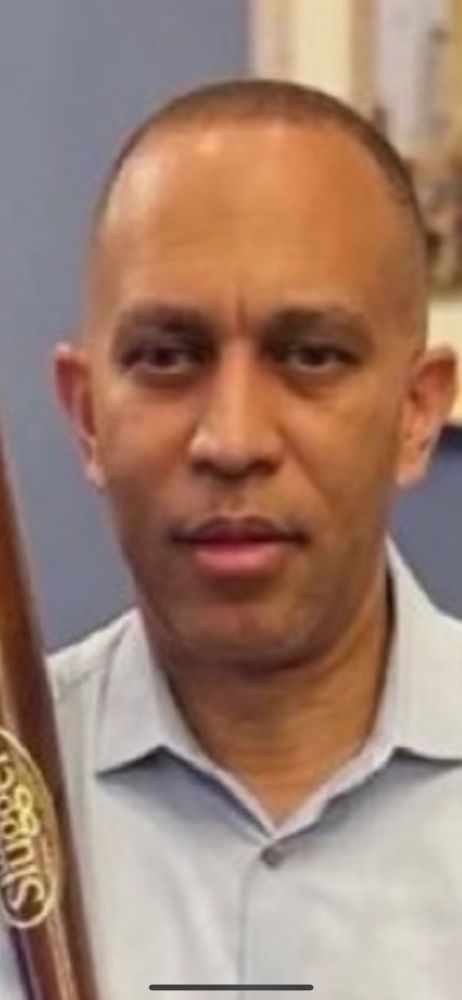 dead-eyes hakeem jeffries posing with a baseball bat 