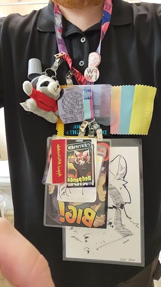Lanyard with a series of badges and artwork on it, mostly red pandas and raccoons 