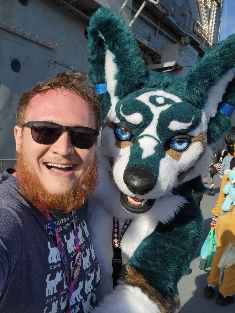 A guy in sunglasses hugging a wolf link fursuit