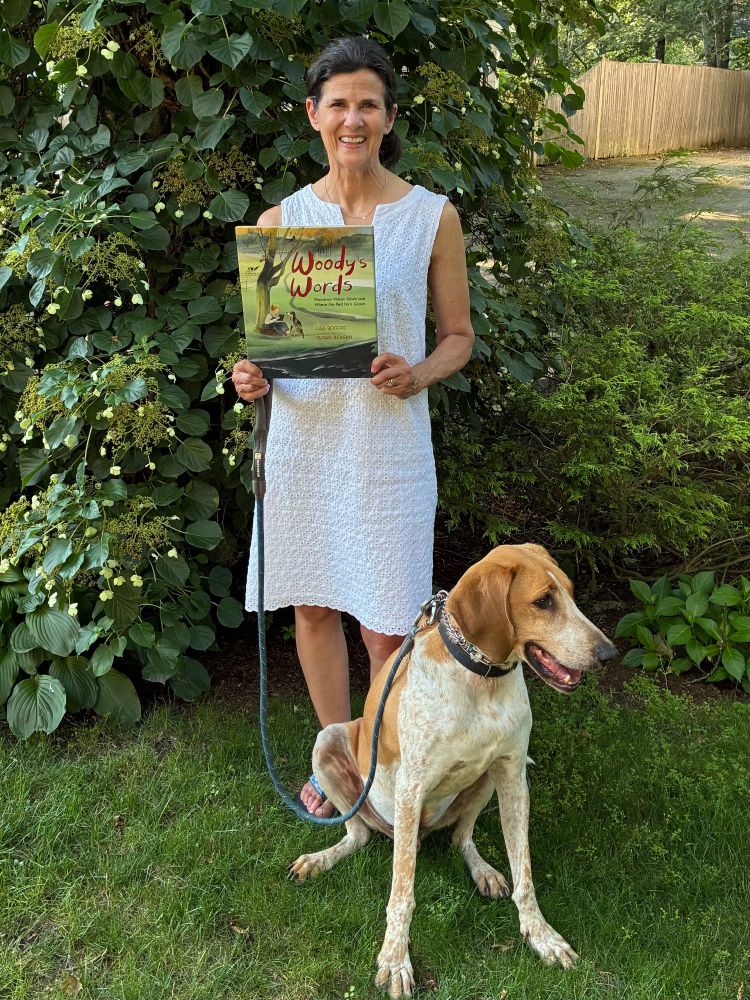 Photo of a hound dog and a person holding the picture book Woody's Words