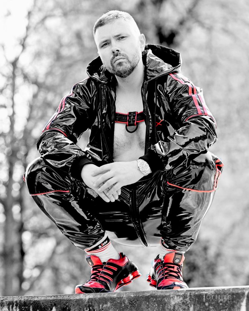 Man in shiny PVC tracksuit, leather bulldog harness and Shox NZ1 