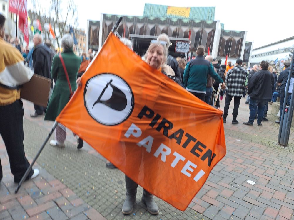 Theaterplatz Krefeld meine Person mit Flagge der #Piratenpartei Flagge orange Logo weiß mit schwarzem Piratensegel Schrift schwarz Piraten Schrift weiß Partei. 