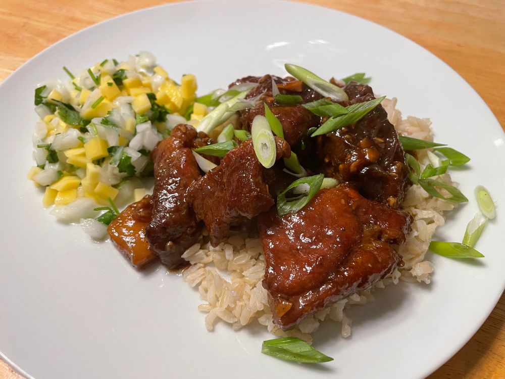 A photo of a plate of pork adobo and mango salsa