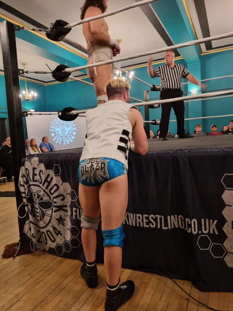 Joe Blazr leaning on the apron like an untrustworthy guy