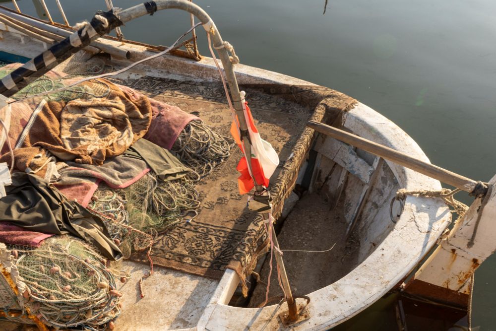 Rugs and fishing nets are piled high on a small boat
Photo by Fatima Joumaa/The Public Source