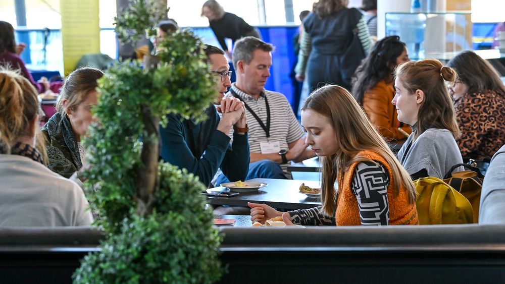 People sit together around tables in a cafe during the MA's 2023 conference