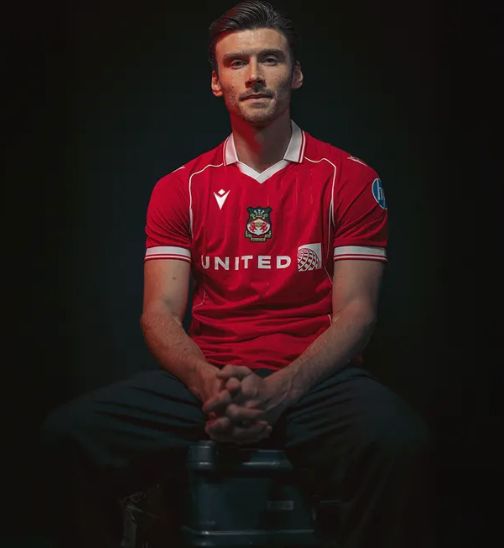 KIeffer Moore posing in his red Wrexham AFC kit in dramatic lighting, smoldering at the camera.