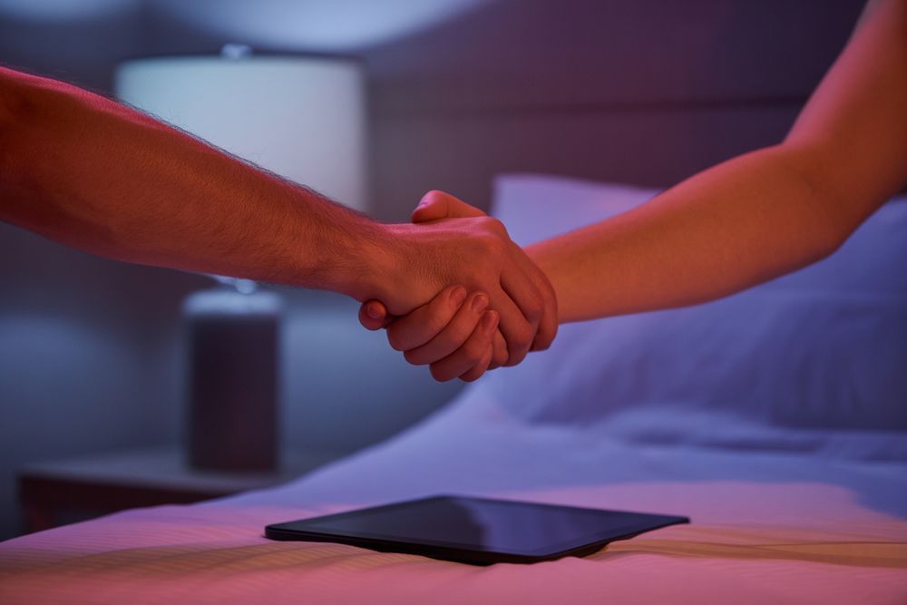 Two hands shaking above an iPad after having done a collaboration in the bedroom.